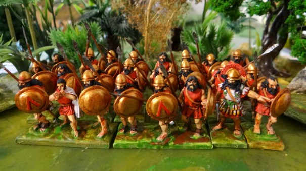 L'hoplite sans cuirasse équipé du casque dit de Pilos qui n'était pas métallique. habituellement le rouge est associé aux tuniques spartiates.